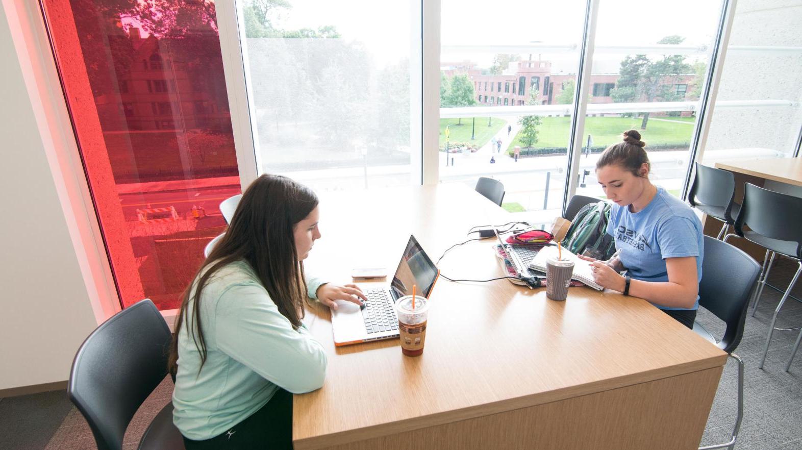 Two female students study at a table in the Learning Commons