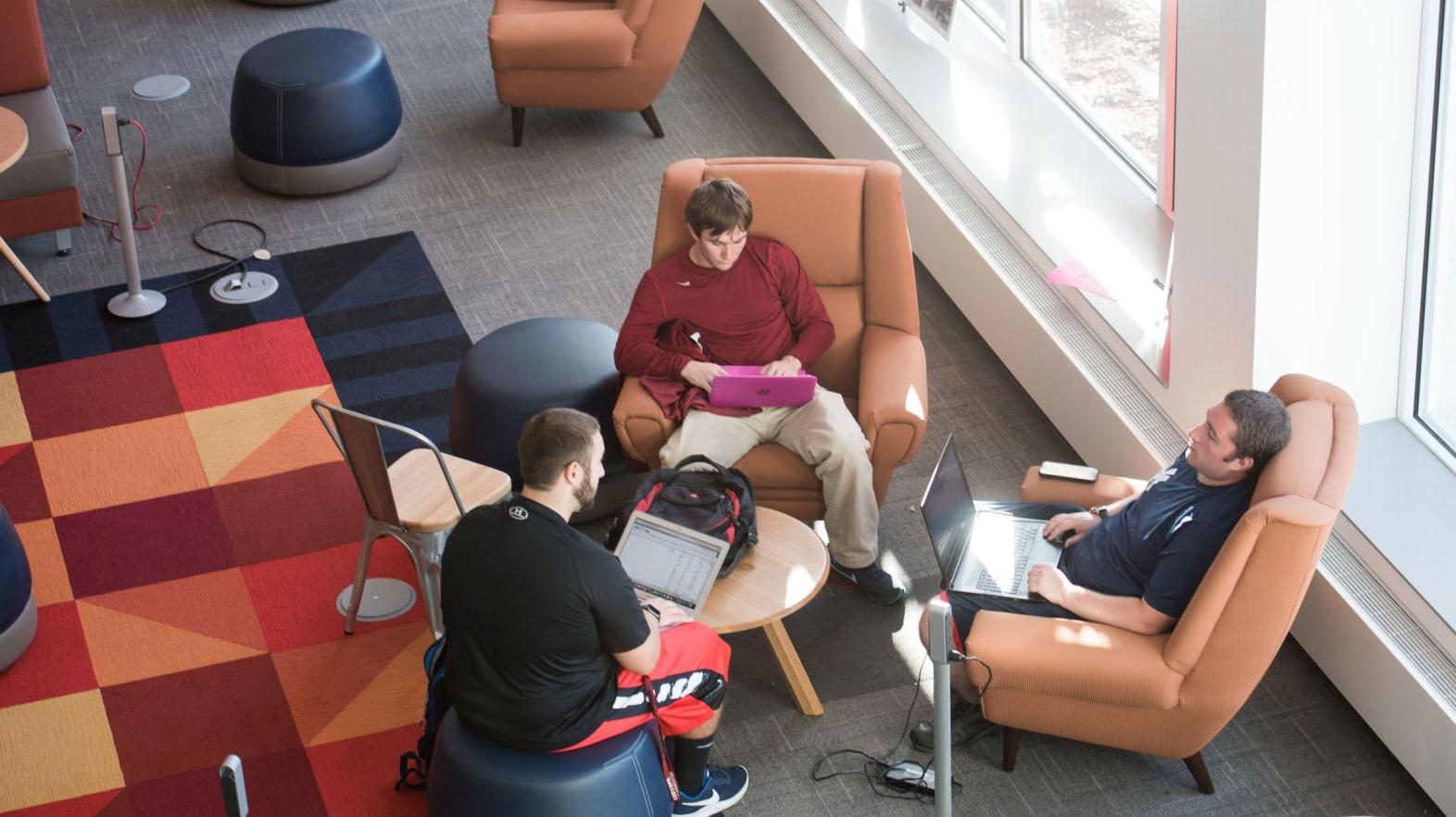 An overhead photo of three male students meeting in the Learning Commons.