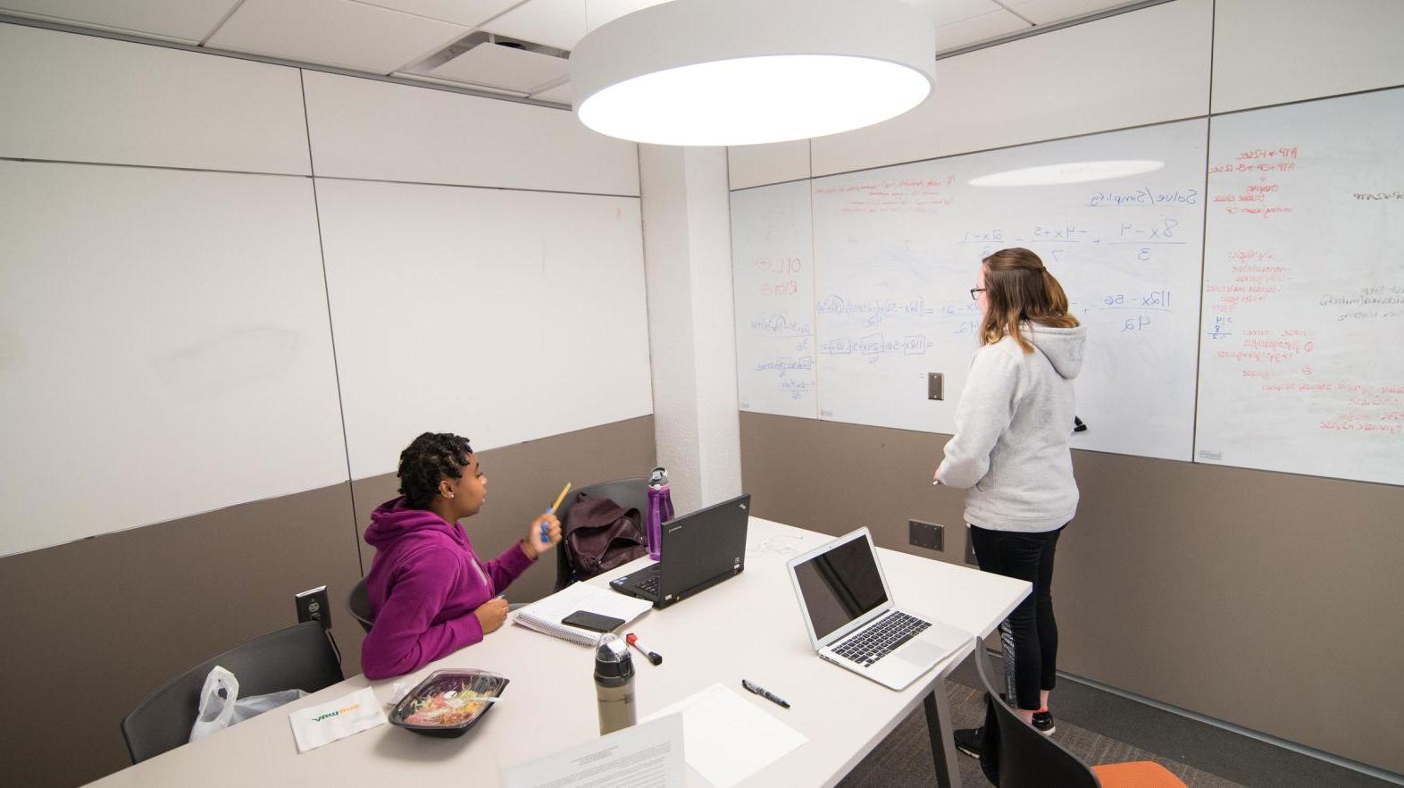 Two student work on the white boards in the Learning Commons.